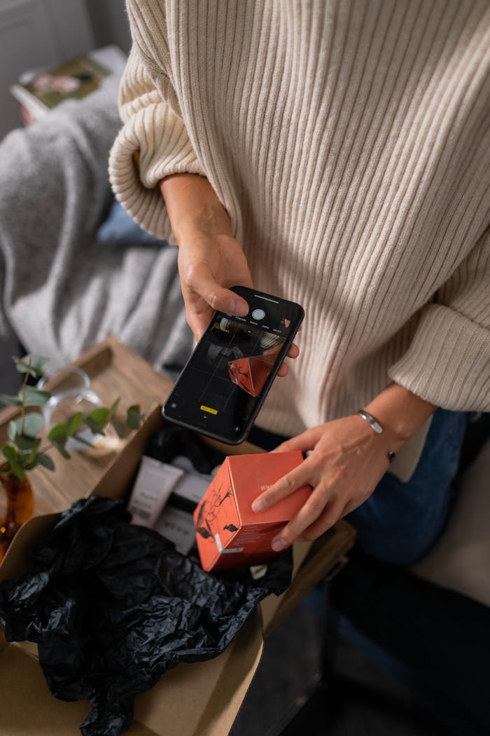 Woman captures product packaging with smartphone, highlighting personal branding.